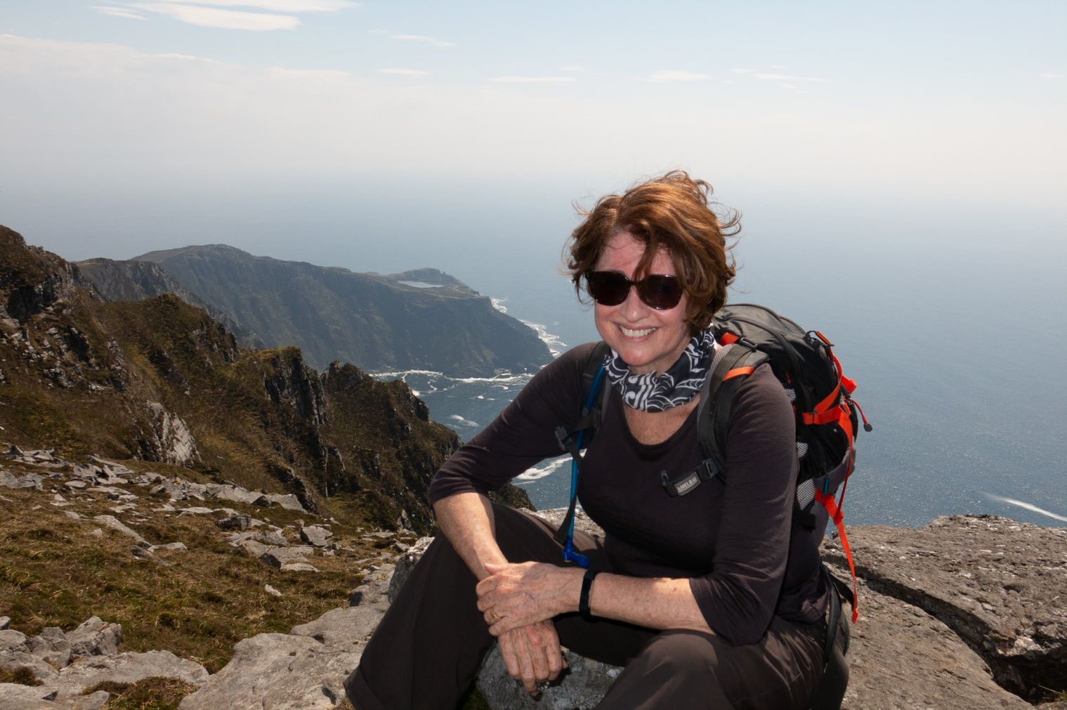 Someone sitting on a mountain overlooking a rugged coastal landscape. Someone sitting on a mountain overlooking a rugged coastal landscape.