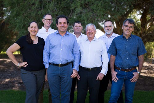 Small group of people standing in front of trees. Small group of people standing in front of trees.
