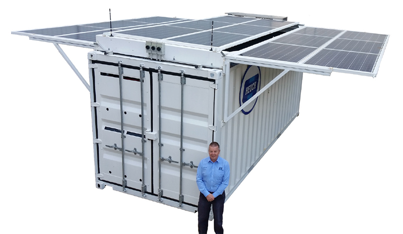 Person standing in front of a white shipping container with solar panels on the top. Person standing in front of a white shipping container with solar panels on the top.