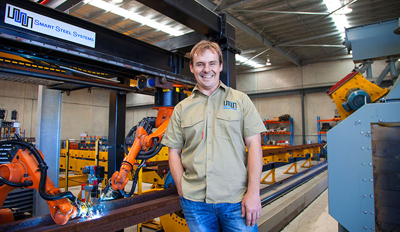 Person standing in front of a production line of robot welding arms. Person standing in front of a production line of robot welding arms.