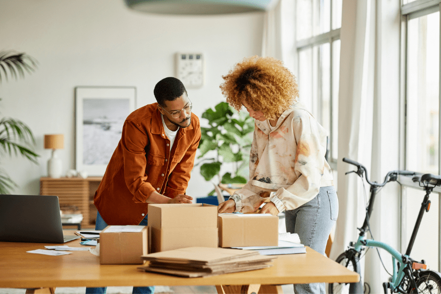 A man and woman at a table packing their products