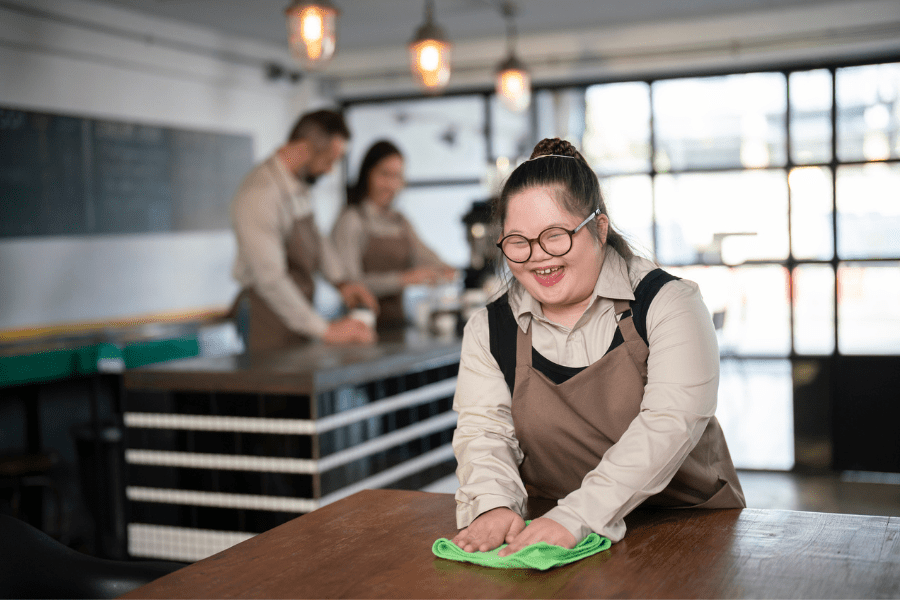 A woman with a disability cleaning a table in a café