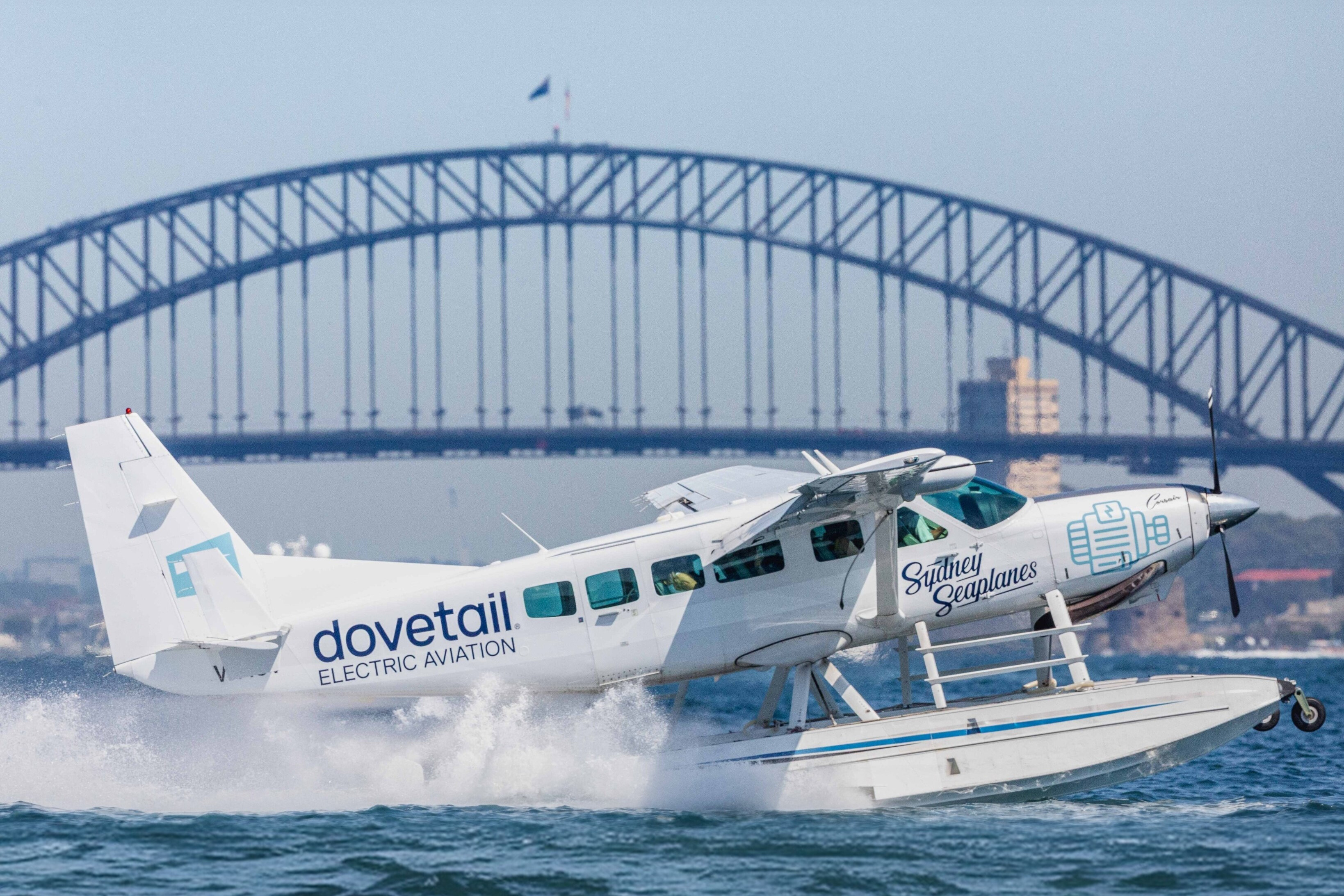 An image of a dovetail aviation aircraft in front of the Sydney Harbour Bridge