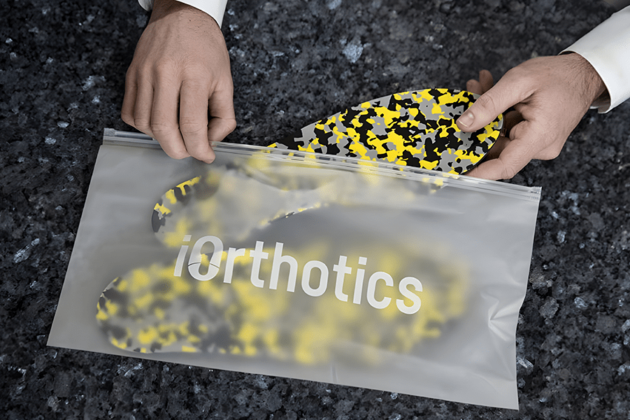 An image of the smart orthotics from iOrthotics. The image consists of a pair of colourful shoe inserts inside a clear plastic case with the words iOrthotics printed on.