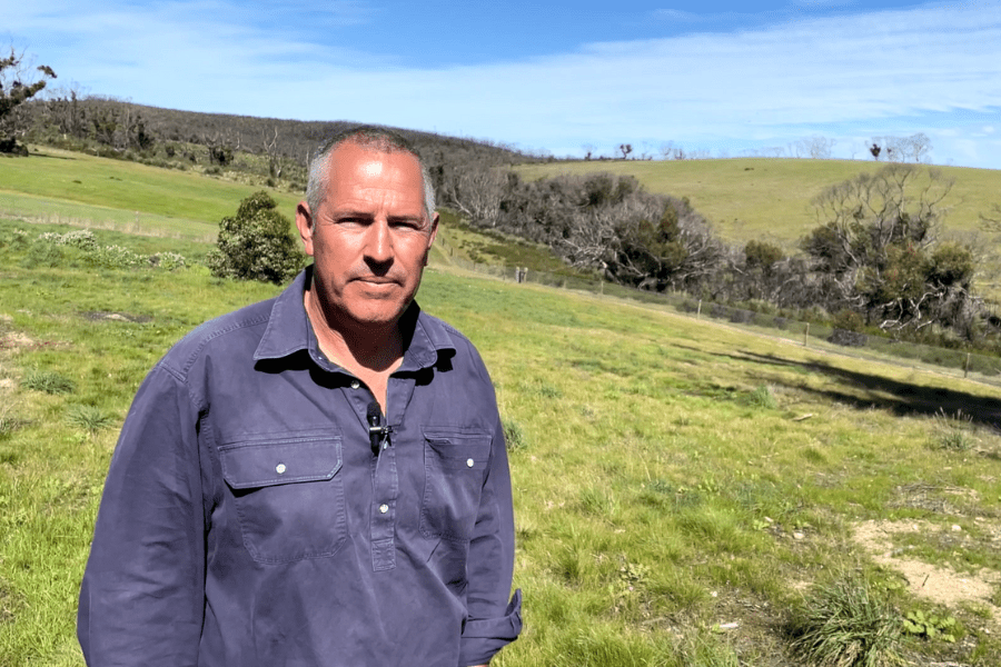 Man standing in front of a paddock and hills