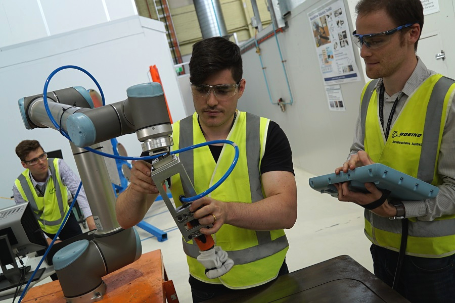 2 people adjusting a robotic in an advanced manufacturing facility