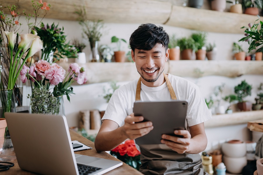 man at a floristry business using a tablet as digital tool