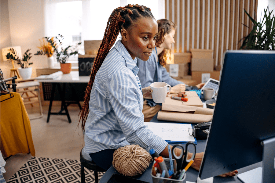 A women sitting at a desk looks at a computer monitor