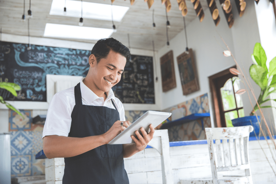 A restaurant owner in his business doing work on a digital tablet