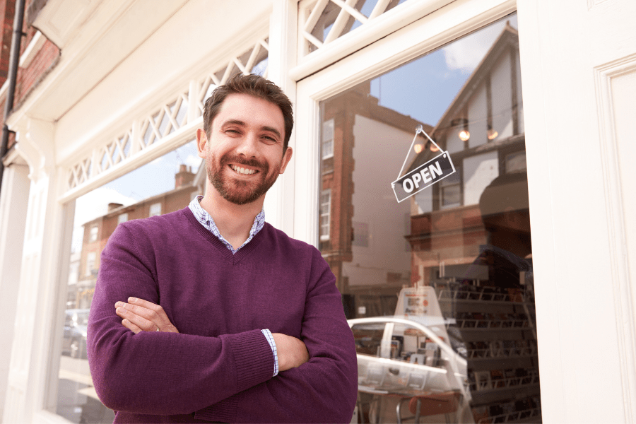 Man standing in front of a shop with an open sign in the glass door