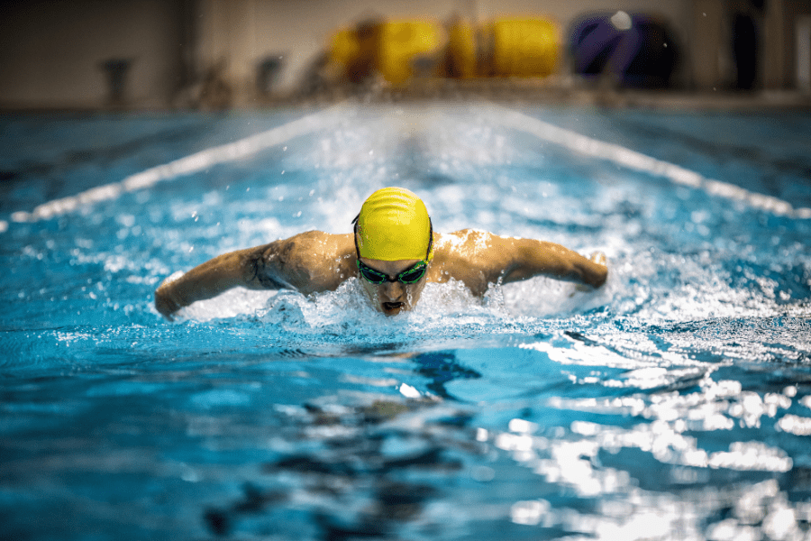 A man wearing goggle and a swimming cap swims laps in a pool